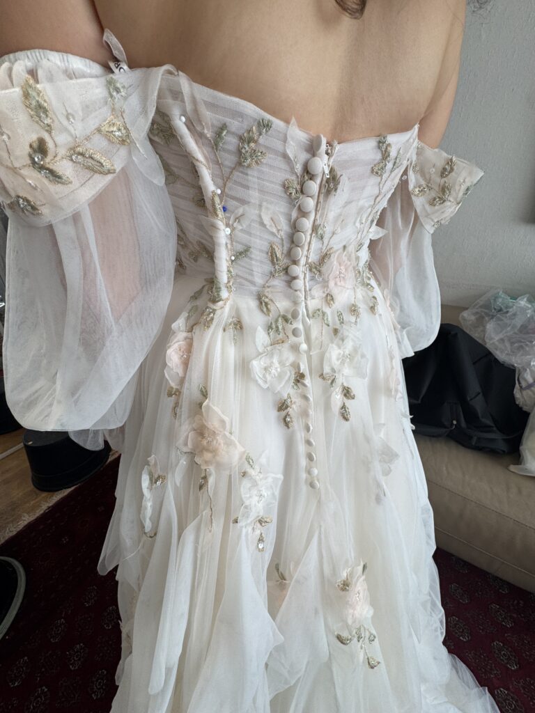 Morilee bridal alterations showing pinned up to be resized back bodice with embroidered tulle and fabric-covered buttons