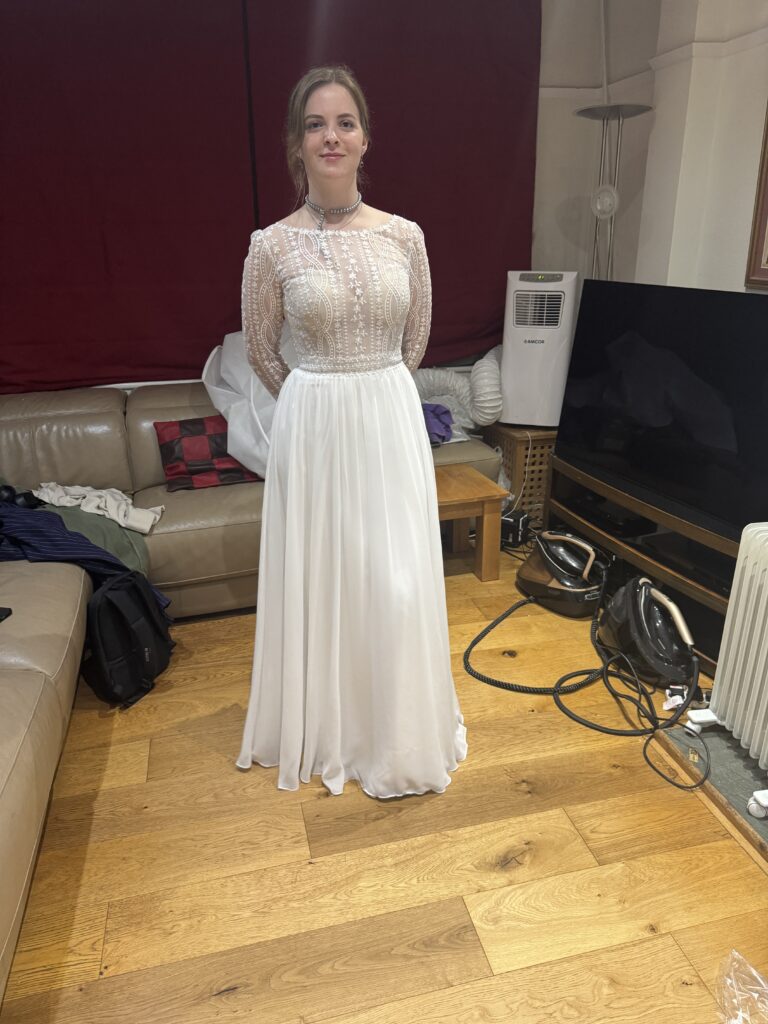 Front view of the bride in her WED2B Marisol wedding dress with sheer patterned sleeves and a chiffon skirt