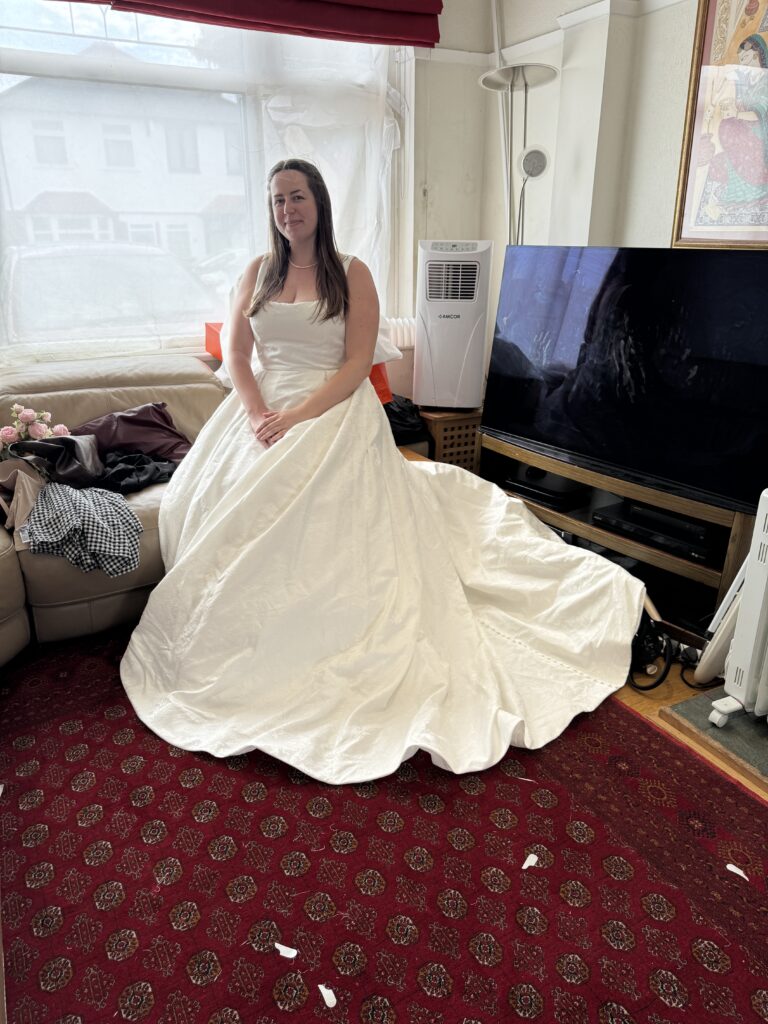 Bride from Oxted seated in ivory Sofia Cruz Florentina wedding dress with square neckline and full ballgown skirt at her Final dress fitting at my Sutton Studio.