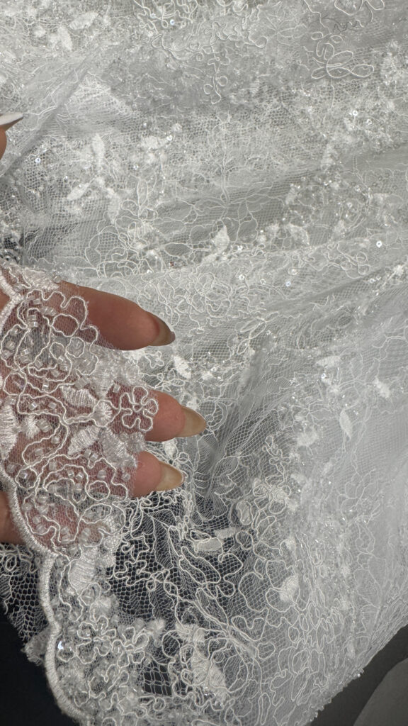 Intricately beaded lace wedding dress hem pinned during shortening of a Yedyna Estia bridal gown.