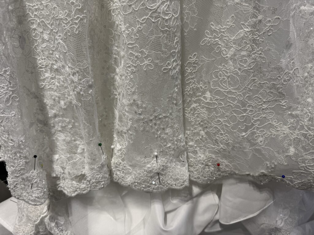 Intricately beaded lace wedding dress hem unpicked during shortening of a Yedyna Estia bridal gown.